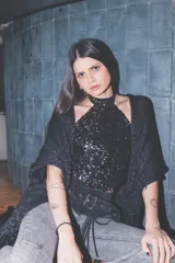 Ruana negra de tejido liviano y brillante, con grandes flecos decorativos en los bordes.