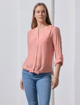 Blusa blanca de gasa marca Zac & Rachel, con cuello a la base, escote en V, abertura central con botones, bolsillo aplicado en el pecho y mangas largas regulables con presilla y botón. Tiene terminación opcional de nudo en el ruedo.