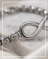 Pulsera de eslabones de acero con dije central en forma de símbolo de infinito.
