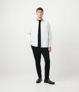 Camisa celeste de algodón, corte oversized, manga larga, cuello camisero, dos bolsillos frontales con solapa y cierre con botones.