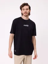 Remera de corte oversize color negro, con cuello redondo y manga corta. Presenta un estampado pequeño en el centro del pecho con el logo de la marca en estilo aerógrafo y una etiqueta pequeña en el ruedo inferior.