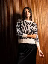 Buzo de tejido de punto con textura suave, diseño de estampado animal print en tonos beige, gris y negro, cuello redondo y mangas largas.