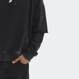 Hoodie oversize de color negro con efecto lavado, diseño de mangas superpuestas, bolsillo frontal tipo canguro y cordones ajustables en la capucha. Presenta un pequeño bordado en el centro del pecho.