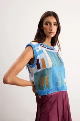 Chaleco de punto tejido a mano con diseño geométrico multicolor en tonos azules, celestes, beige y marrón, sin mangas y con escote redondo.