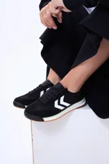 Championes urbanos de estilo retro, color negro con detalles en blanco y suela de goma color caramelo. Presentan un diseño con paneles superpuestos y el logo característico de la marca en el lateral.