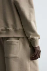 Bermuda de algodón color beige, estilo jogger, con corte relajado, cintura elástica ajustable con cordón y bolsillos laterales y trasero.