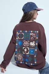 Remera de manga larga negra con cuello redondo y puños blancos visibles, presentando un estampado gráfico con motivos celestiales en el pecho.