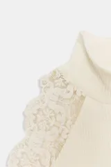 Top ajustado de tejido acanalado color crema, con cuello perkins y sisa adornada con aplicación de encaje a tono.