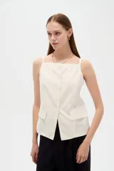 Top de viscosa color blanco con tirantes finos, cuello a la base y cierre frontal con botones. Presenta bolsillos appliqués con solapa en la parte inferior y diseño al cuerpo.