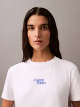Remera blanca de algodón con cuello redondo y logo Calvin Klein aterciopelado en azul.
