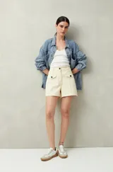 Short de tiro alto color beige, con bolsillos delanteros con solapa y botones a la vista.