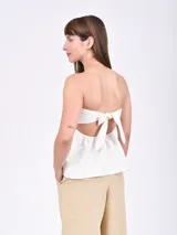 Top strapless de color crudo, con diseño entallado en el busto y corte ligeramente acampanado en la cintura.