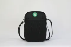 Morral cruzado de nylon negro con ribetes y detalles en verde. Presenta un parche con el logo de los Boston Celtics en la parte superior y un logo de la NBA en la parte inferior frontal. Incluye correa regulable.