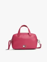 Cartera tipo bowling de Tommy Jeans, color fucsia, con doble asa superior y correa ajustable extraíble. Presenta logo metálico de la marca en la parte frontal.