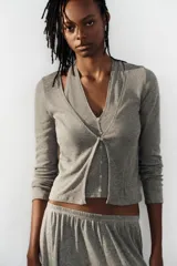 Top de punto efecto doble color gris melange, con diseño de cuello en pico, tirantes tipo halter interiores y cierre frontal con botones. Cuenta con mangas largas.