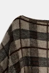 Capa de punto con cuello redondo y diseño asimétrico, con estampado de cuadros en tonos tierra y negro.