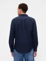 Camisa de corte clásico confeccionada en tejido Oxford, color verde oliva. Presenta cuello abotonado, cierre frontal con botones, mangas largas con puños abotonados y un bolsillo en el pecho con el logo del oso Brannan bordado.