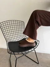 Sueco de estilo casual confeccionado en símil gamuza color marrón, con interior y borde superior revestido en corderito sintético color crema. Presenta una suela de plataforma plana de goma en tono marrón oscuro.