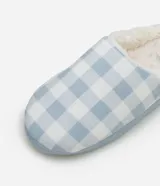 Pantufla cerrada para mujer con diseño a cuadros en tonos celeste y blanco, forro interno de corderito sintético y suela plana en tono celeste claro.