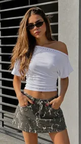 Minifalda de denim con estampado camuflado en tonos grises y negros, de tiro bajo y diseño ajustado.