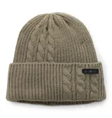 Gorro de lana tejido con diseño de trenzas y canalé, color verde oliva. Cuenta con un borde doblado y una etiqueta con el logo de la marca Columbia. Incluye un forro interior de polar para mayor calidez.
