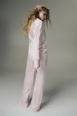 Pijama de dos piezas en tejido fluido de satén color rosado con ribetes en color contrastante. Camisa de manga larga con cuello abierto, botones adelante y bolsillo superior abierto, junto con un pantalón de pierna amplia.