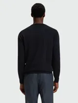 Buzo de punto fino con cuello redondo y mangas largas, confeccionado en lana virgen. Presenta un diseño minimalista con el logo de la marca bordado sutilmente en el pecho.