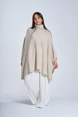 Poncho tejido color beige, con cuello alto y corte asimétrico.