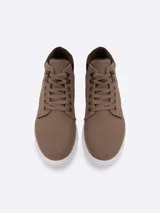 Bota urbana de caña media confeccionada en gamuza color marrón, con cuello acolchado en contraste, sistema de cordones con ojalillos metálicos y suela plana blanca.