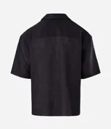 Camisa de lino blanca de corte boxy, manga corta, cuello bowling y cierre frontal de botones.