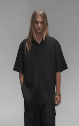 Camisa de manga corta con calce oversize, confeccionada en tejido de lyocell, con cuello clásico y cierre frontal de botones.