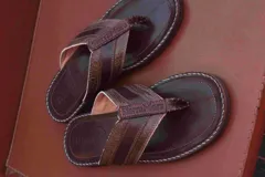 Sandalias tipo ojotas de cuero color marrón claro con tiras de cuero marrón oscuro.