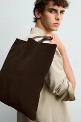 Bolso tipo shopper de diseño minimalista, confeccionado en piel con acabado de serraje. Cuenta con dos asas largas de mano y un compartimento principal espacioso con un bolsillo interior con cierre.