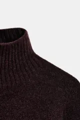 Vestido corto de punto con cuello subido, manga larga y sisa ancha. Presenta un detalle de costura vertical marcada en el centro del delantero y acabados en rib en cuello, puños y ruedo.