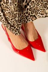 Zapato de tacón con tira trasera, color negro charol, con punta fina y tacón geométrico.