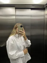 Camisa blanca de mangas largas abullonadas con puños fruncidos y cuello alto con volados.