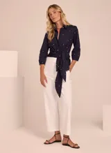 Blusa azul marino con estampado de lunares blancos, cuello camisero, mangas 3/4 y lazo en la cintura.