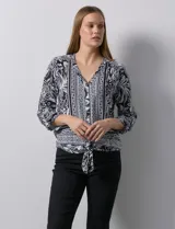 Blusa estampada con escote en V y abertura con botones. Largo de manga regulable con presilla y botón. Terminación de ruedo con nudo.