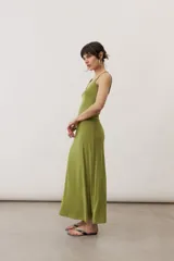 Vestido largo color verde suave, sin mangas, con escote redondo y silueta al cuerpo que se ensancha levemente hacia el dobladillo.