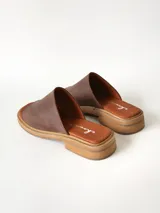 Sandalias de cuero color chocolate, con faja ancha en el empeine, plantilla de gamuza y suela plana con taco bajo.