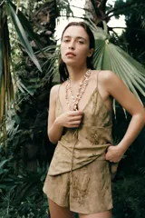 Shorts de tiro bajo con cintura elástica y detalle de pliegues en el delantero. Presenta un diseño estampado con motivos florales en tonos tierra.