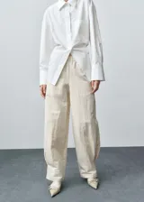 Pantalón de diseño balloon con cintura elástica, tiro medio y pinzas en el bajo. Presenta una textura ligeramente arrugada y forro interior.