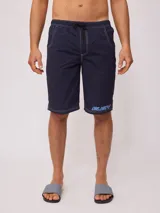 Short de baño azul marino con cintura elástica ajustable con cordón, bolsillos laterales y logo de la marca Rusty estampado en azul en la pierna izquierda.