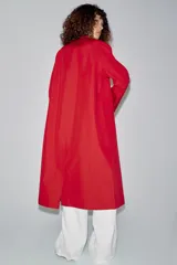 Trench largo color rojo de la línea ZW Collection de Zara, con cuello solapa, manga larga y bolsillos laterales ocultos. Presenta un diseño con forro interior a contraste y cierre frontal con botones a presión.