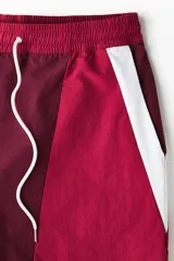 Short deportivo de nylon en bloques de color rojo, bordó y blanco. Cuenta con elástico revestido y cordón de ajuste blanco en la cintura, bolsillos laterales, aberturas cortas en el bajo y suspensor interior de malla.