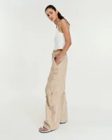 Pantalón cargo de tiro medio confeccionado en gabardina de algodón y lino con efecto gastado. Presenta una silueta de pierna recta y ancha, con bolsillos laterales inclinados y bolsillos cargo con tapa en las rodillas. Incluye tiras ajustables con hebillas metálicas en los laterales para modificar la silueta, cierre metálico y bolsillos traseros.