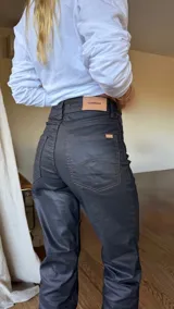 Pantalón negro de tela impermeable engomada con tajo en el tobillo y pespuntes color óxido.