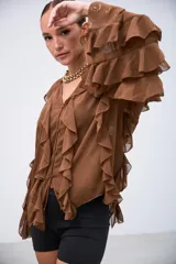 Blusa de gasa color marrón con volados en el frente y en las mangas largas. Presenta cierre frontal con botones y un diseño holgado con caída fluida.
