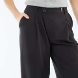 Pantalón ancho de talle alto en color negro, con diseño amplio y fluido, bolsillos laterales y cierre frontal oculto.