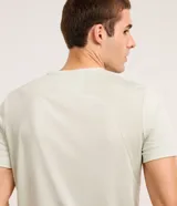 Remera deportiva color verde claro, de corte regular, con cuello redondo y mangas cortas. Presenta un pequeño estampado con letras en el pecho y un recorte en la espalda.